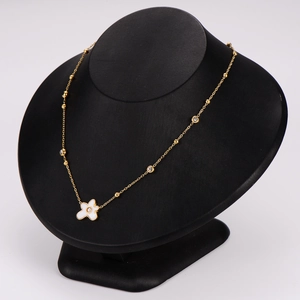 Elegant gold necklace with clover pendant and white shell inlay on a black mannequin bust