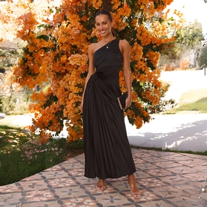 Elegant black one-shoulder pleated maxi dress with flowy skirt in outdoor floral setting