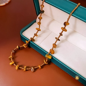 Detail shot of tiger eye stone bead necklace emerging from an elegant green jewelry box