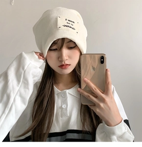 Detail of cream white knit beanie featuring vintage style EL MICRAER patch design