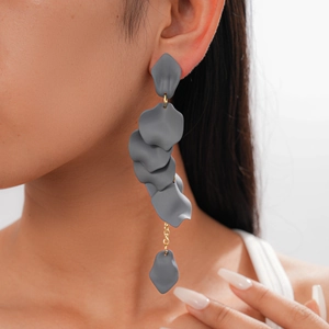 Detail of grey acrylic petal tassels and gold chain earrings on model for a retro look