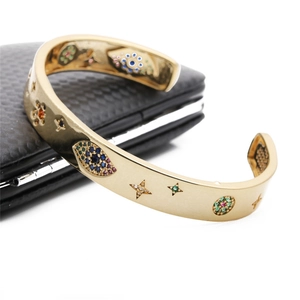 Detailed close-up of gold enamel cuff bracelet with evil eye and star patterns