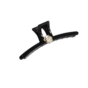 Elegant black camellia hair claw clip with white flower and gold trim on white background