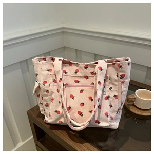 Close-up of pink corduroy tote bag with strawberry prints and functional outer pockets