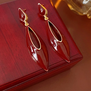 Detail of vintage teardrop enamel earrings with gold borders on a wooden jewelry box