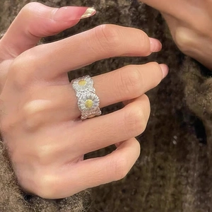 Detailed view of silver daisy ring featuring two 3D floral motifs with yellow stamens