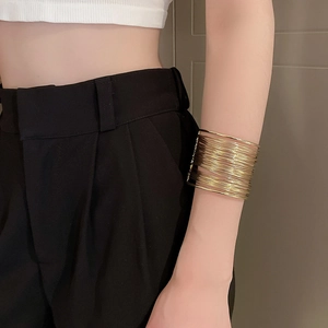 Detail of minimalist layered gold wire cuff bracelet on model arm in natural light