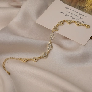 Detailed close-up of gold heart airplane bracelet with lobster clasp and zircons