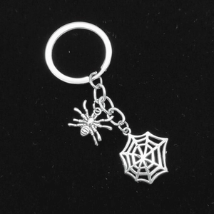 Macro detail of silver metal spider and spiderweb pendants on Halloween keychain