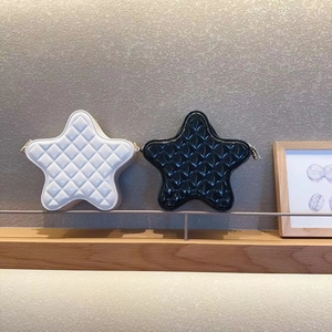 Close-up of star-shaped quilted chain bags in black and white on a wooden shelf
