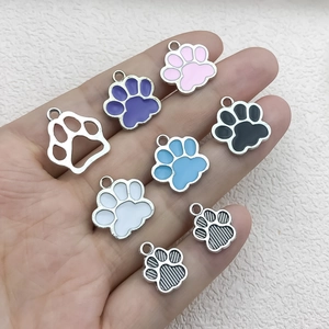 Hand holding various colorful cat paw alloy pendants for DIY keychain accessories