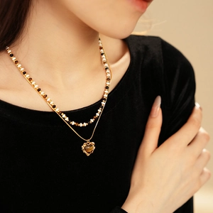 Detail of double-layer necklace featuring tiger eye heart pendant and beaded chain