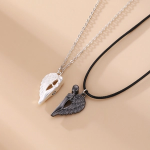 Detail of silver and black angel wing couple necklaces with heart magnets on beige base