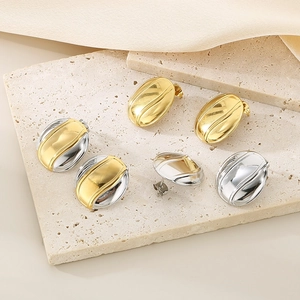 Polished 18K gold and silver oval coffee bean stud earrings on a stone base