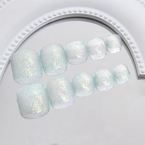 Glittery holographic holographic light blue press-on toenails on a reflective mirror base