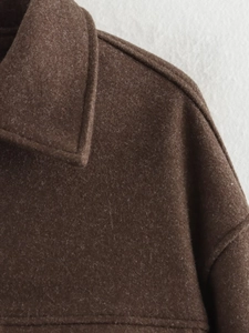 Dettaglio del colletto di un cappotto in lana marrone scuro con cuciture e trama del tessuto