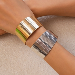 Detailed view of wide gold and silver cuff bracelets with hammered metal texture