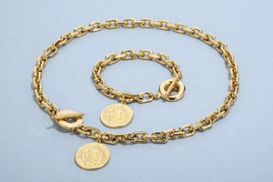 Detail of chunky gold chain jewelry set with coin portraits and toggle clasp
