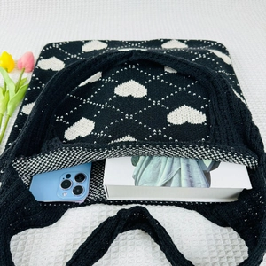 Interior view of black knitted tote with heart patterns showing capacity for phone and book