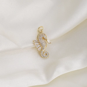 Macro shot of a golden seahorse pendant set with clear zircons on white silk
