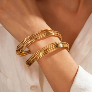 Close-up of gold geometric twisted multi-layer cuff bracelet on female wrist