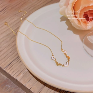 Close-up of golden heart pendant necklace on white ceramic plate with a rose flower