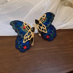 Macro detail of blue embroidered butterfly earrings with crystals and gold metal base