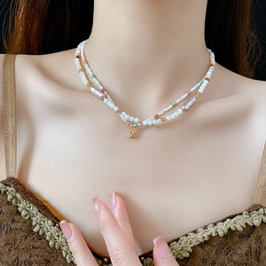 Detail of layered necklace featuring white seed beads, faux pearls and gold accents