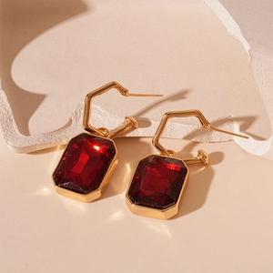 Detail of vintage gold earrings featuring rectangular dark red faceted gemstone pendants