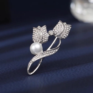 Macro d'une broche tulipe argentée avec cristaux étincelants et une perle blanche ronde