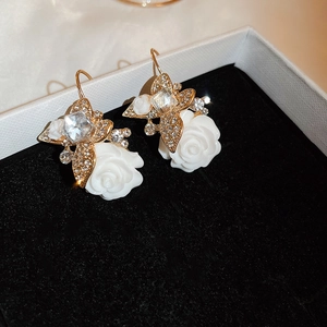 Détail de boucles d'oreilles vintage en or avec roses en résine et papillons en cristal