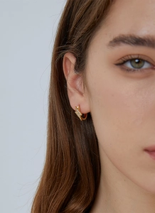 Close-up of gold lightning bolt earrings with pavé zircons worn by a female model