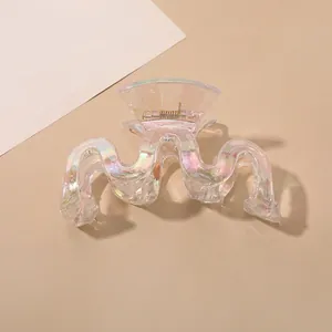 Detail of iridescent wave hair claw clip showing polarized rainbow finish and gold spring