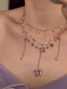 Detail of layered gold necklace featuring purple butterfly pendant and star charms on neck