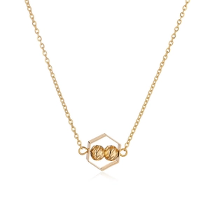 Close-up of golden necklace with hexagonal geometric pendant and faceted double beads