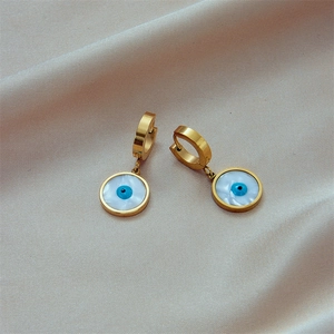 Golden round earrings with blue evil eye mother of pearl inlay on white satin background