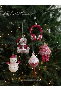 Close-up of glittery red and pink Christmas ornaments hanging on a green tree