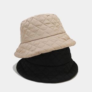 Detail showing two quilted bucket hats with diamond stitching in beige and black colors