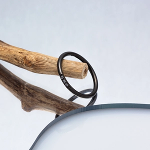 Detail of minimalist black titanium steel ring with three crystals on a branch