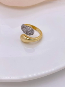 Macro detail of gold plated horseshoe ring featuring a teardrop end and cubic zirconia pavé