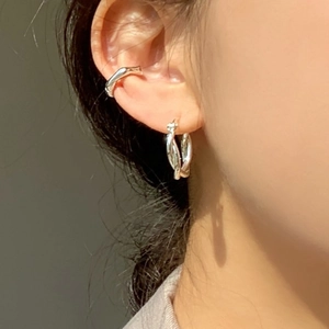 Detail of twisted 925 silver hoop earring and cuff worn by a model on the ear