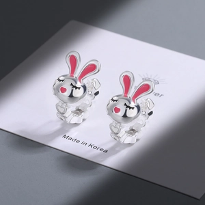Detail of silver bunny earrings with pink enamel coating on a clean card base