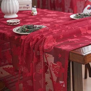 Elegant red lace Christmas table runner with star and bell patterns on wood