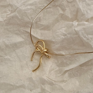 Minimalist gold bow pendant necklace with slim chain on elegant textured background