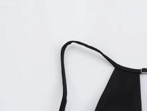 Détail de la couture renforcée de la bretelle et du connecteur métallique sur la robe noire
