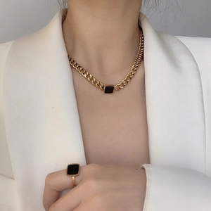Golden chunky chain necklace and ring set with black square stones on a model