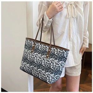 Détail du sac cabas imprimé léopard avec bandoulières en cuir marron et rivets