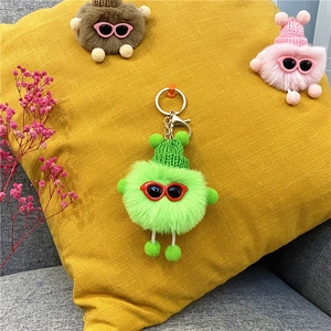 Detail of green plush soot sprite keychain with knit hat and red sunglasses on metal ring