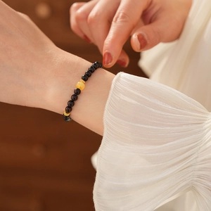 Detail view of sandalwood beaded bracelet with amber centerpiece on a woman's wrist