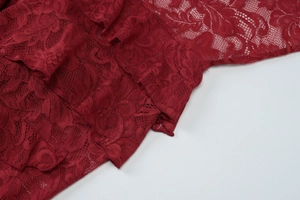Close-up detail of high-quality red lace fabric with intricate floral mesh patterns
